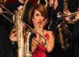 Singer Raye surrounded by instrumentalist