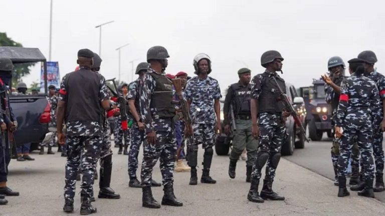 Police officers displaying seized cash, houses, and a vehicle after busting a ₦7.7bn telecom data fraud syndicate in a major operation.