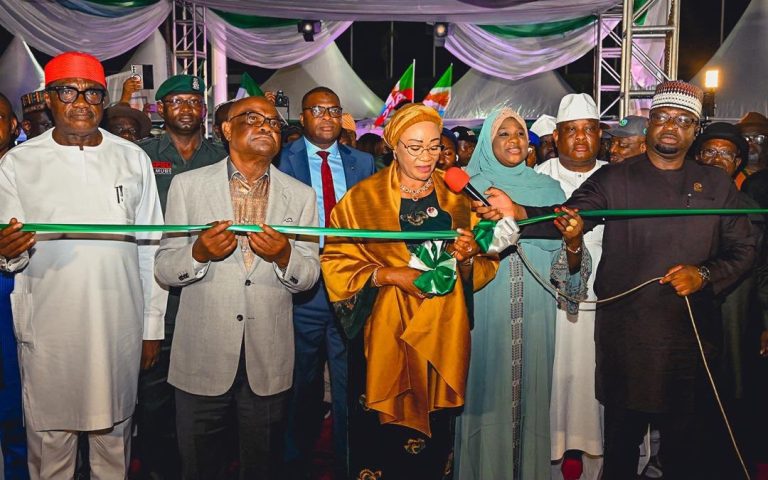 First Lady Unveils the Remodeled Abuja City Gate Nigeria's First Lady standing before the newly remodeled Abuja City Gate during its official unveiling ceremony.